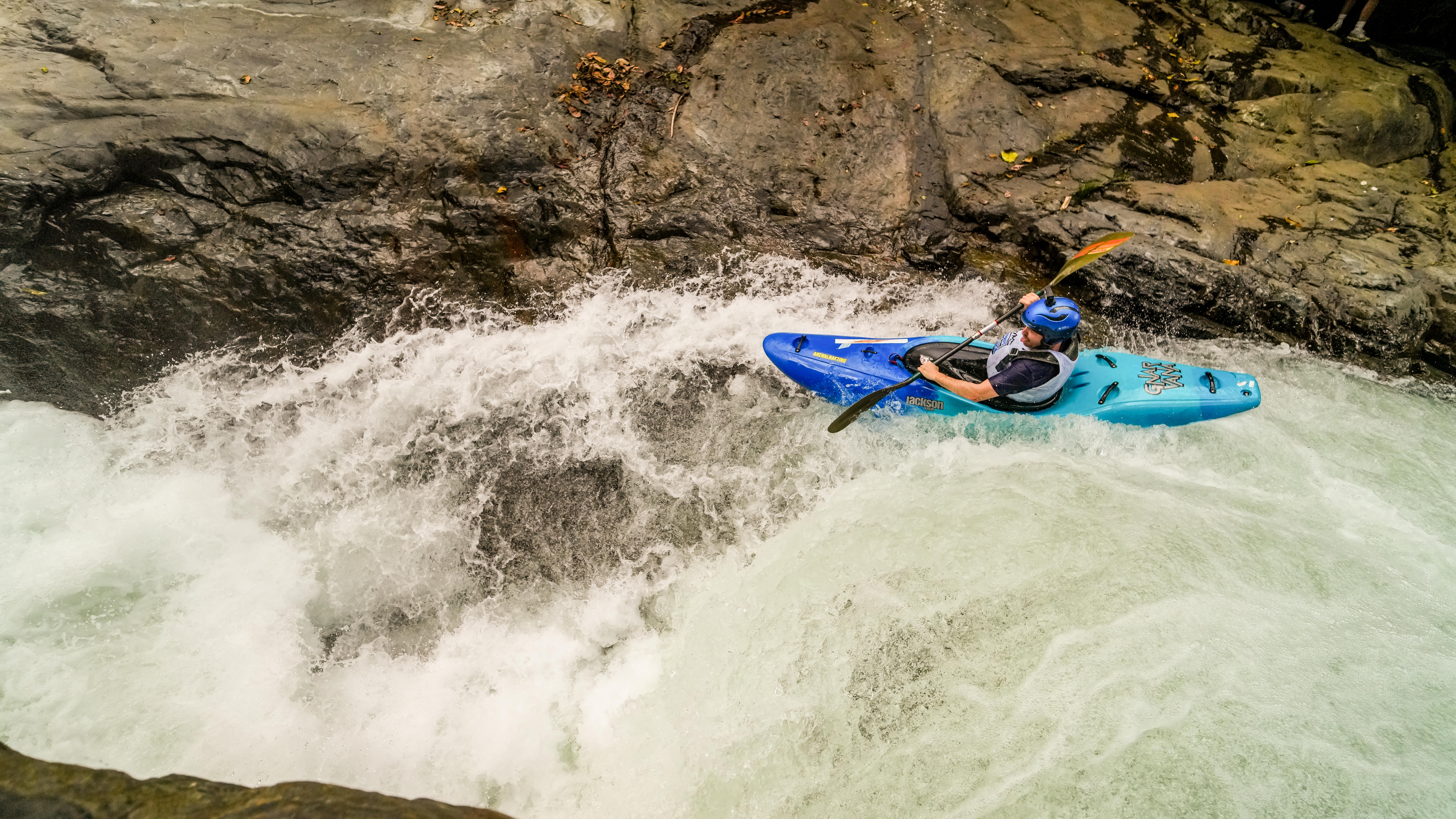 Kayaker in a blue boat on the rapid